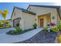 Tan house with brown garage door, walkway, landscaping, and a wreath on the front door at 364 Palmaria Ct, Nokomis, FL 34275
