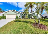 House exterior features a light green color, well-maintained lawn, and palm trees at 6001 Cedarwood Ln, Bradenton, FL 34203