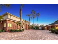 Elegant two-story brick home featuring a spacious brick driveway, lush landscaping, and mature palm trees at 7800 18Th W Ave, Bradenton, FL 34209