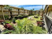 Lush courtyard with tropical landscaping, seating area, and a two-story building at 11485 Oakhurst Rd # 200-220, Largo, FL 33774