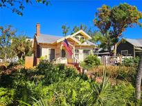 Charming two-story home featuring mature landscaping, a brick chimney, and a welcoming front porch with the American flag at 1667 Laurel St, Sarasota, FL 34236