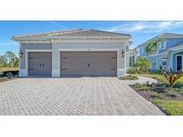 Two-car garage, light gray exterior, paved driveway, landscaping at 10142 Crystal Isles Cir, Sarasota, FL 34241
