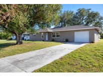 Single-story home featuring a long driveway, neutral stucco exterior, and attached garage at 12302 Tangier St, North Port, FL 34287