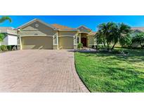 Front exterior of a single-Gathering home with a three-car garage and large driveway at 13951 Wood Duck Cir, Lakewood Ranch, FL 34202