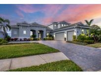 Two-story home with three-car garage, paver driveway, and landscaped yard at 7940 Redonda Loop, Bradenton, FL 34202