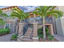 Exterior view of a two-story condo building with palm trees and a stairway at 13816 Messina Loop # 203, Bradenton, FL 34211