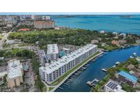 Stunning aerial view of waterfront condos with boat docks and city skyline in the background; perfect luxury living at 1703 N Tamiami Trl # 210, Sarasota, FL 34234