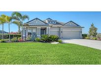 Gray house with two-car garage, landscaping, and a large front yard at 1825 Twin Rivers Trl, Parrish, FL 34219