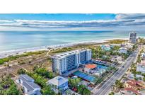 Stunning aerial view of a beachfront condo complex with tennis courts and a pool, near the ocean at 420 Beach Rd # 203, Sarasota, FL 34242