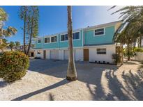 Brand new light teal three-unit building with attached garages and paved driveway at 303 65Th St # B, Holmes Beach, FL 34217