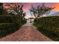 Long brick driveway leading to a charming two-story home with mature trees and manicured landscaping at 4110 Riverview Blvd, Bradenton, FL 34209