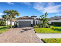 Single-story home with gray garage door, paver driveway, and lush landscaping at 5397 Bartolomeo St, Sarasota, FL 34238