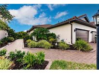 Landscaped walkway leads to a charming house with a brown door and two-car garage at 6226 Plateau Ct, Bradenton, FL 34203