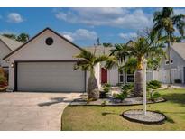 Charming home showcasing a two-car garage, manicured lawn, and tropical landscaping with vibrant palm trees at 7806 Ontario Street Cir # 7806, Sarasota, FL 34243