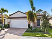 Single-story home with white garage door, landscaping, and brick pavers at 153 Soliera St, Nokomis, FL 34275