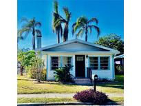 Charming bungalow with a white exterior, black door, and lush landscaping at 222 27Th W St, Bradenton, FL 34205