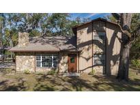 Two-story house with stone and wood siding, a brown door, and large windows at 6919 64Th E Ave, Palmetto, FL 34221