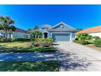 Charming blue single-story home with a two-car garage and landscaped yard at 1387 Still River Dr, Venice, FL 34293