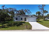 Newly constructed one-story home with a white garage door and landscaping at 1859 Lamont St, North Port, FL 34288