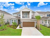 Two-story home with attached garage, balcony, manicured lawn, and beautiful landscaping at 33443 Landsman Loop, Wesley Chapel, FL 33543