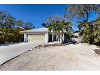 Cute bungalow with a light gray exterior, wood garage door, and tropical landscaping at 633 Calle De Peru, Sarasota, FL 34242