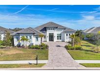 Two-story home with gray roof, white siding, and a paver driveway at 8544 Pavia Way, Bradenton, FL 34202