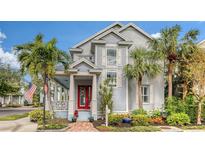 Charming two-story home boasts a bright red front door and lush landscaping, enhanced by palm trees at 1775 Stapleton St, Sarasota, FL 34239