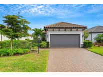 House exterior featuring a gray garage door, landscaping, and a brick driveway at 4727 Motta Ct, Bradenton, FL 34211