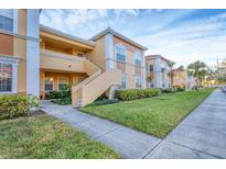 Exterior view of a two-story condo building with a walkway, lush landscaping, and palm trees at 1130 Villagio Cir # 203, Sarasota, FL 34237