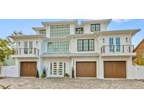 Striking three-story coastal home featuring a symmetrical design, three-car garage, and charming Juliette balconies at 329 Tarpon St, Anna Maria, FL 34216