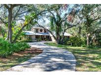 House with circular driveway, surrounded by lush landscaping and mature trees at 4938 Hubner Cir, Sarasota, FL 34241