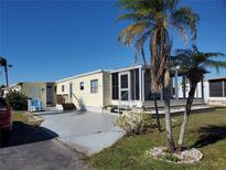 Single-wide yellow manufactured home with a screened porch and palm trees at 5414 Burma Ct, Bradenton, FL 34207