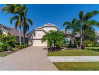 Attractive home with paver driveway, lush landscaping, and palm trees at 7223 Orchid Island Pl, Bradenton, FL 34202