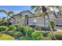 Gray house with nicely landscaped front yard, walkway, and palm trees at 8753 Pebble Creek Ln, Sarasota, FL 34238