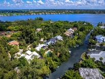 Stunning aerial view of waterfront homes surrounded by lush greenery and a beautiful blue bay at 1214 Sea Plume Way, Sarasota, FL 34242