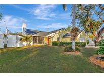 Bright yellow house with a red door, neatly manicured lawn, and palm trees at 5101 Island Date St, Sarasota, FL 34232