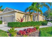 Front exterior view of a home with a one-car garage, lush landscaping, and palm trees at 2520 Terracina Dr, Venice, FL 34292