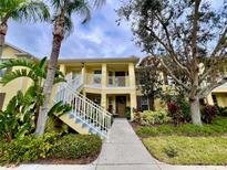 Inviting yellow two-story condo featuring a private balcony, lush landscaping, and a welcoming entrance at 5611 Key West Pl # 5611, Bradenton, FL 34203