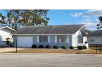Charming single-story home with a gray exterior, attached garage, and landscaped front yard at 214 Genet Ct, Sun City Center, FL 33573