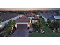 Beautiful single-story home with a red tile roof, manicured landscaping, and a paver driveway at twilight at 4730 Zeno Ct, Bradenton, FL 34211