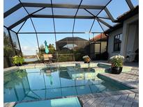 Relaxing screened-in pool with a sitting area, beautiful plants and view of the lake at 7130 Whittlebury Trl, Bradenton, FL 34202