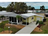 Charming yellow home with a manicured lawn, mature trees and landscaping at 8411 Regal Way, Palmetto, FL 34221