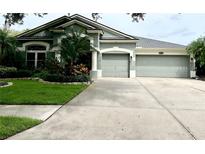 House exterior featuring a two-car garage and well-manicured lawn at 19025 Fern Meadow Loop, Lutz, FL 33558