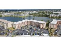 Aerial view of condo building with lake, landscaping, and large parking lot with plenty of parking spaces at 3937 Lake Bayshore Dr # 401, Bradenton, FL 34205