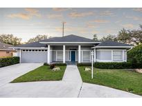 Gray house with blue door, columned porch, and landscaped yard at 566 Oak Bay Dr, Osprey, FL 34229