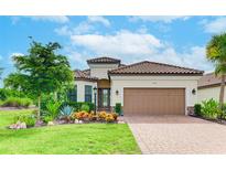 Charming home featuring a tile roof, brick paver driveway, well-manicured lawn, and colorful garden at 4707 Arpino Ct, Bradenton, FL 34211