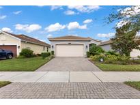 Single-story home with a two-car garage and landscaped front yard at 4905 Avila Lakes Dr, Wimauma, FL 33598