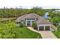 Beautiful waterfront home with lush landscaping, brick driveway, and a charming entrance with double garage at 609 Colonial Bay Dr, Nokomis, FL 34275