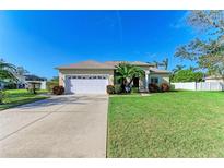 Single-story house with a two-car garage, lush lawn, and mature landscaping at 1605 21St W Ave, Palmetto, FL 34221