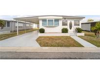 Front view of a single-wide manufactured home with carport and landscaping at 3403 Overcup Oak Ter, Sarasota, FL 34237